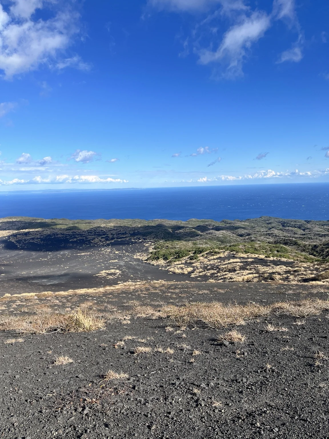 黒い大地の向こうに青い海が広がる裏砂漠の景観